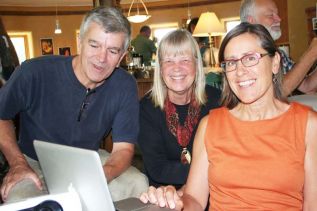 St. Lawrence College’s Steve Lapp, Wintergreen Studios founding president Rena Upitis and activist Angela Bischoff look over the afternoon schedule at the Power in the Climate Era seminar last Saturday at Wintergreen Studios.